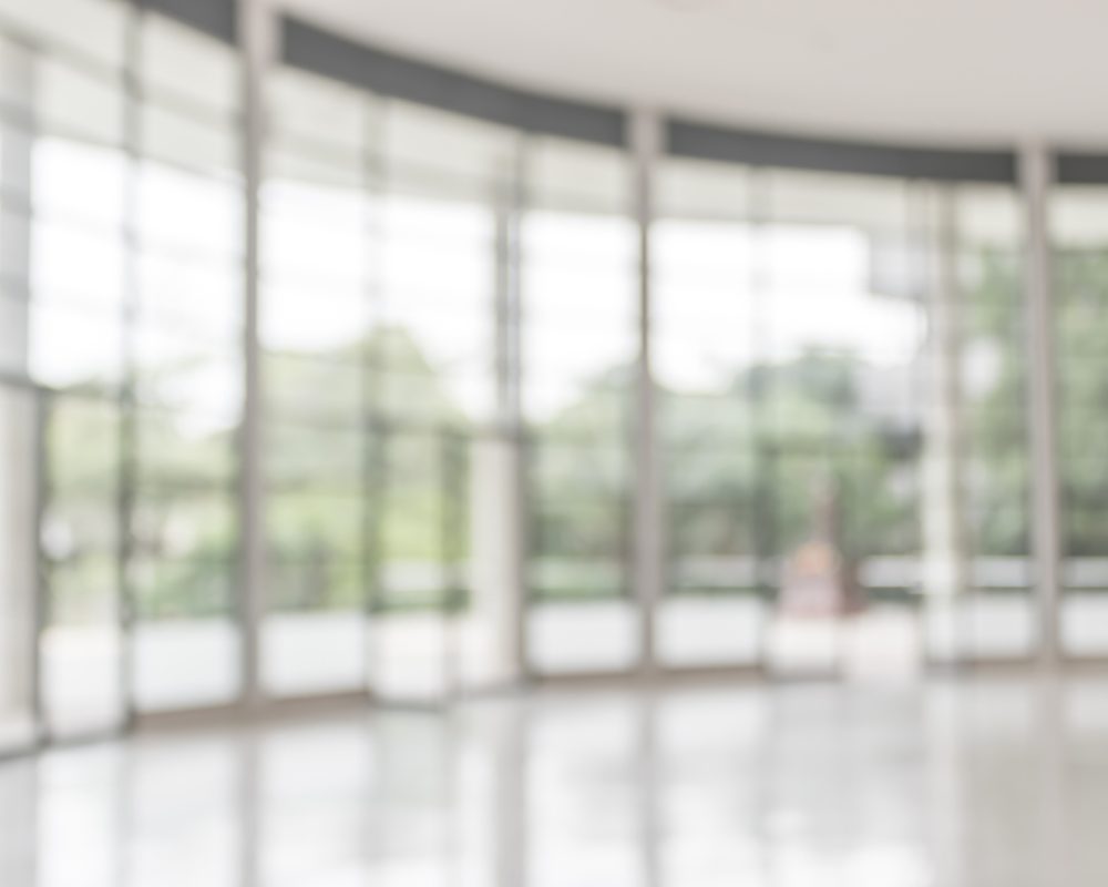 Blur background interior view looking out toward to empty office lobby and entrance doors and glass curtain wall